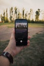 Closeup shot of a man's hand holding a phone and taking pictures of a beautiful summer landscape Royalty Free Stock Photo