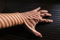 Closeup shot of a man's hand on a table with jalousie shadows