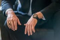 Closeup shot of a man wearing a suit, more precisely: his hands, ring, and wristwatch