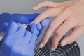 Closeup shot of manicurist in blue rubber gloves cleans cuticle on female nails using a milling cutter for manicure Royalty Free Stock Photo