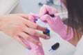 Closeup shot of manicurist in pink rubber gloves makes hand painting fingernails with brush Royalty Free Stock Photo