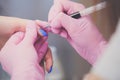 Closeup shot of manicurist in pink rubber gloves makes hand painting fingernails with brush Royalty Free Stock Photo