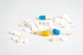Closeup shot of many little white and colorful tablet capsules on a white background