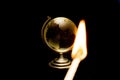 Closeup shot of a match with fire and a globe on the black background Royalty Free Stock Photo