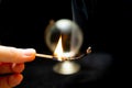 Closeup shot of a match with fire and a globe on the black background Royalty Free Stock Photo