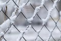 Closeup shot of a metal net fence covered in snow Royalty Free Stock Photo