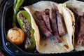 Closeup shot of Mexican beef tacos with a roasted jalapeno and onion in a plastic container