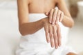 Closeup shot of middle aged woman applying drop of moisturising cream on hands, using nourishing lotion for dry skin