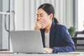 Closeup shot of millennial Asian young stressed depressed sleepy female businesswoman employee sitting holding hand on messy hair Royalty Free Stock Photo