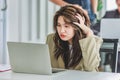 Closeup shot of millennial Asian young stressed depressed sleepy female businesswoman employee sitting holding hand on messy hair Royalty Free Stock Photo