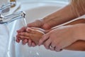 Washing germs and dirt straight down the drain. Closeup shot of a mother helping her little girl wash her hands at the