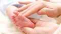 Closeup shot of mother touching and stroking little feet of her newborn baby. Concept of family happiness and loving Royalty Free Stock Photo