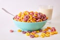 Closeup shot of multicolored fruity cereals and glass milk isolated on a white background