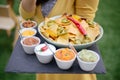 Closeup shot of nachos with chilies on a bowl with different kinds of dip on the side