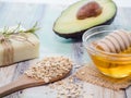 Closeup shot of natural skincare product ingredients: avocado, honey, oat flakes, and natural soap