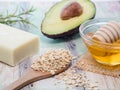 Closeup shot of natural skincare product ingredients: honey, avocado, oat flakes, and natural soap
