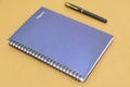 Closeup shot of notebook with a ballpen beside it on a brown background Royalty Free Stock Photo