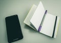 Closeup shot of a notebook with a grey and purple pen on it next to a phone Royalty Free Stock Photo