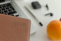 Closeup shot of a notebook planner on a laptop with orange fruit on a table Royalty Free Stock Photo