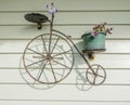 Closeup shot of an old-fashioned bicycle decoration on a wall with a potted flower