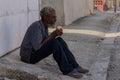 Closeup shot of an old homeless male eating bread on ground outdoors in Matanzas in Cuba