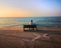 Closeup shot of an old male sitting on the bench near the sea