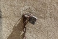 Closeup shot of an old and rusty lock and chains attached to a wall outside during a sunny day Royalty Free Stock Photo