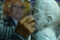 Closeup shot of an old sculptor hands sculpting a face in his workshop with blur background