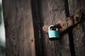 Closeup shot of an old wooden door locked with a green padlock. Royalty Free Stock Photo