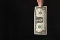 Closeup shot of one dollar bill held by a pair of fingers on a black background Royalty Free Stock Photo