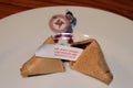 Closeup shot of an opened fortune cookie with a prediction inside in a white plate