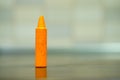 Closeup shot of an orange crayon on a reflective surface