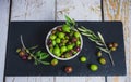 Closeup shot of organic olives in a ceramic bowl, on a black plate, on a wooden table Royalty Free Stock Photo