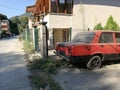 Closeup shot of an out of-order red car parked on the street, near the house Royalty Free Stock Photo