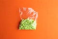 Closeup shot of packaged green round confetti on an orange background