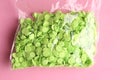 Closeup shot of packaged green round confetti on a pink background