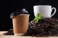 How many cups do you drink a day. Closeup shot of a paper cup on a surface, with a teacup and mint leaf resting on a