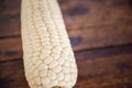 Closeup shot of a peeled single corn ear on a wooden table