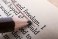 Closeup shot of a pencil underlining and pointing at the word Freedom