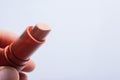 Closeup shot of a person holding a beige lipstick isolated on a grey background Royalty Free Stock Photo