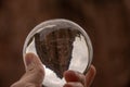 Closeup shot of a person holding a crystal ball with the reflection of historic buildings