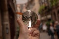 Closeup shot of a person holding a crystal ball with the reflection of historic buildings