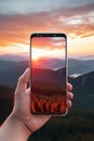closeup shot of person holding mobile phone in hand and taking photo of sunset at sea, nature photography with Royalty Free Stock Photo