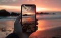 closeup shot of person holding mobile phone in hand and taking photo of sunset at sea, nature photography with Royalty Free Stock Photo