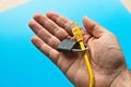 Closeup shot of a person holding a yellow cable and lock over a blue surface Royalty Free Stock Photo