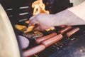 Closeup shot of a person putting cheese on the beef burger on the grill near hot dogs Royalty Free Stock Photo