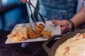 Closeup shot of a person putting chicken pieces on the white plate