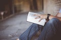 Closeup shot of a person sitting down on the ground and reading the bible with blurred background Royalty Free Stock Photo