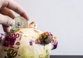 Closeup shot of a person tossing a coin into a piggy bank