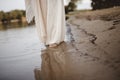 Closeup shot of a person wearing a biblical robe walking on the shore with a blurred background